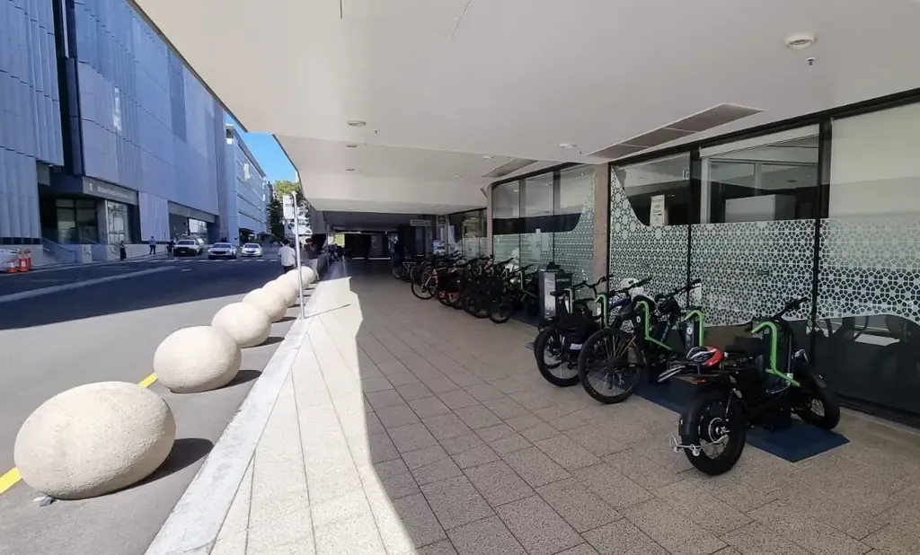 Bikes and e-bikes docked at Bikeep e-bike charging stations along a covered walkway beside Union Road at UNSW Sydney